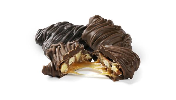 Two chocolate-covered caramel-topped candy bars on a white background, with one broken open to show the caramel filling.