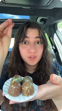 Woman holding Kilwins Dubai chocolate truffles in a car