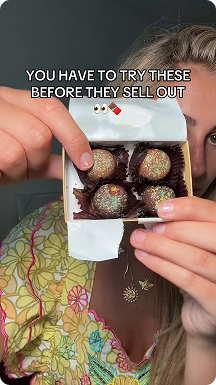 Reviewer holding a box of Kilwins Dubai chocolate truffles