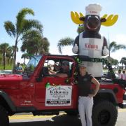 Photo of store owners riding in parade in Jeep with Kilwins the Moose logo