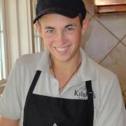 Photo of male Team Member smiling wearing Kilwins hat and apron