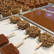 Photo of an array of Caramel-dipped products on trays: Apples, Krispies, & trays of Caramel