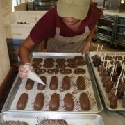 Photo of Team Member drizzling confections with Chocolate