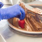 Photo of strawberry being dipped in Chocolate